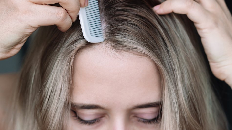Kobieta przeczesująca grzebieniem włosy z widocznymi baby hair