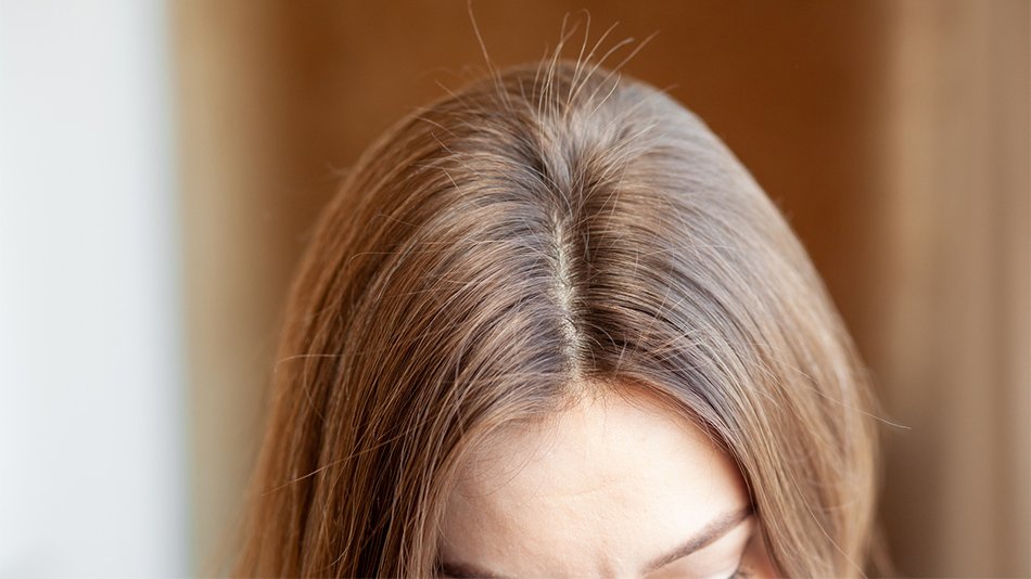 Kobieta przeczesująca grzebieniem włosy z widocznymi baby hair
