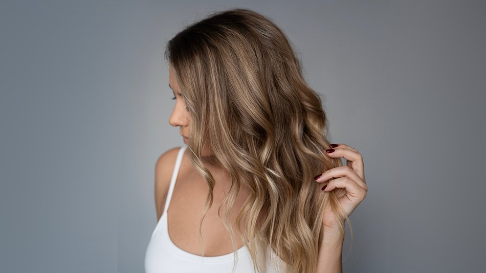 Profil kobiety z twarzą zasłoniętą pofalowanymi blond włosami
