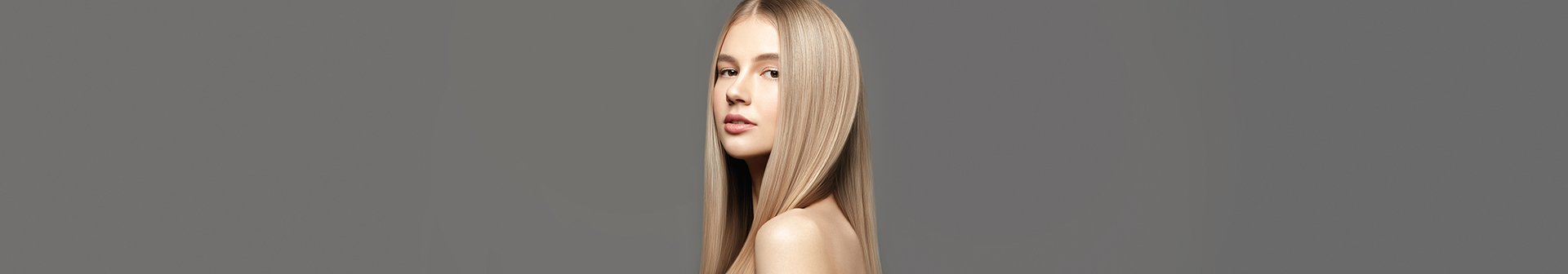 Młoda kobieta z prostymi blond włosami na szarym tle.