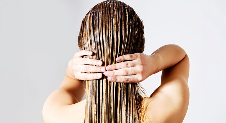Widoczna z tyłu kobieta z prostymi włosami blond z nałożoną maską koloryzującą