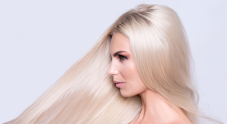 Boczny profil blondynki o platynowych, długich włosach, jasne tło