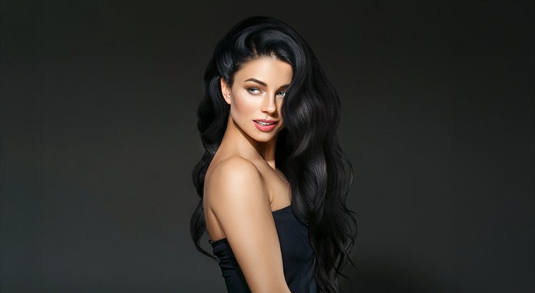 Kobieta z długimi czarnymi włosami na ciemnym tle.