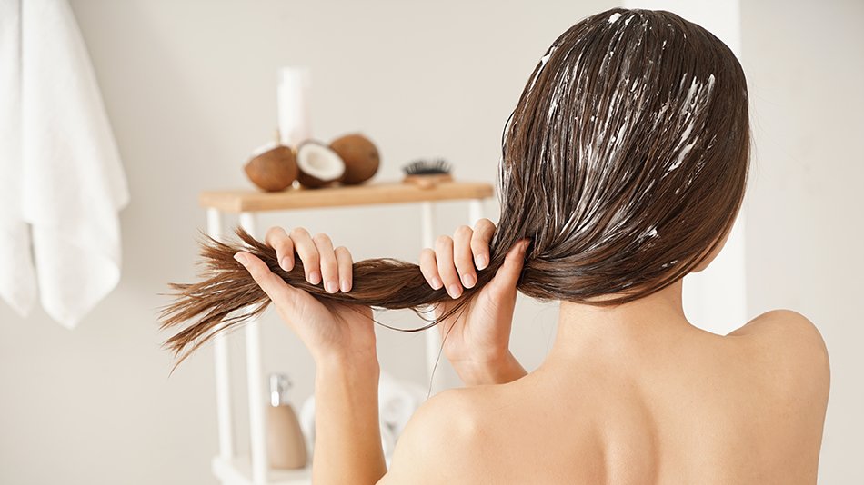 Kobieta odwrócona tyłem nakłada maskę na mokre włosy