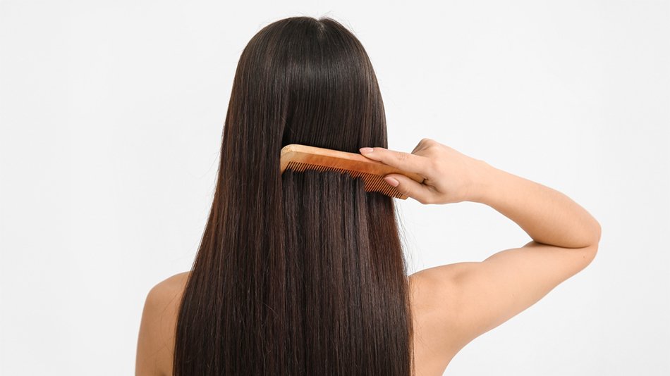 Kobieta przeczesująca grzebieniem długie proste włosy
