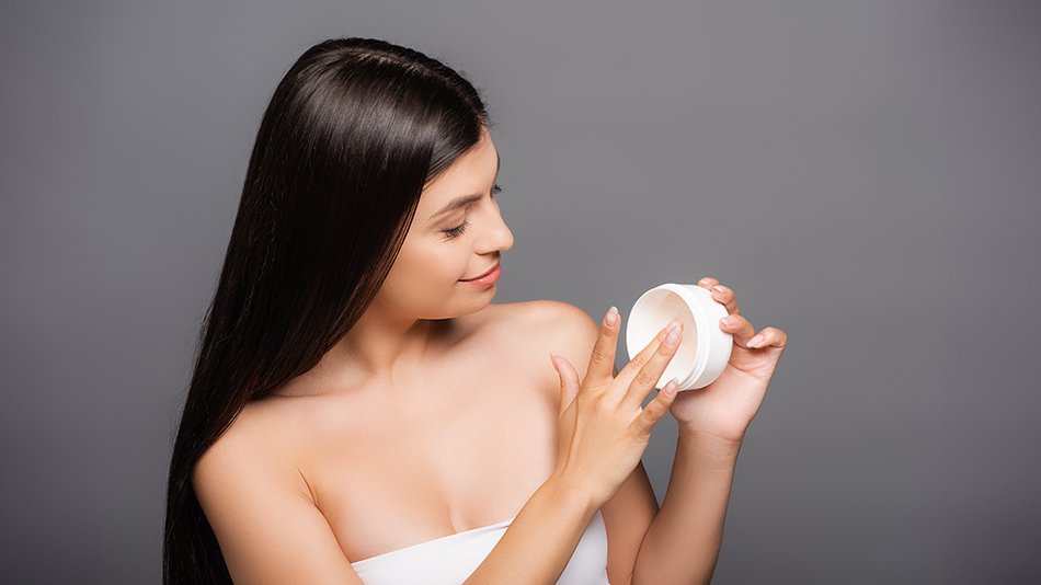 Kobieta nabiera ze słoiczka maskę do włosów