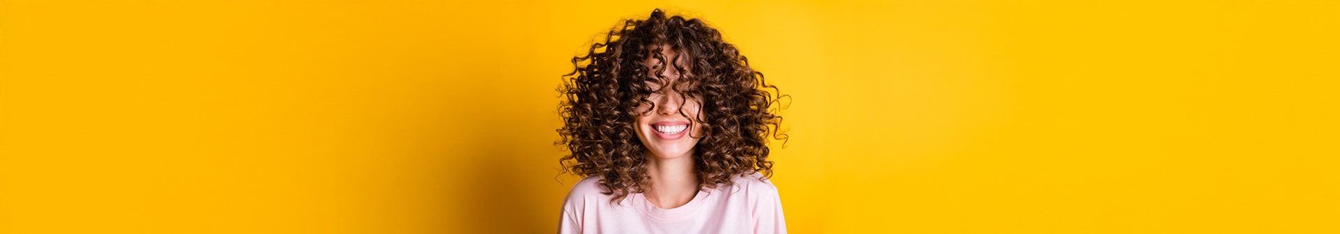Śmiejąca się kobieta z mocno kręconymi włosami.