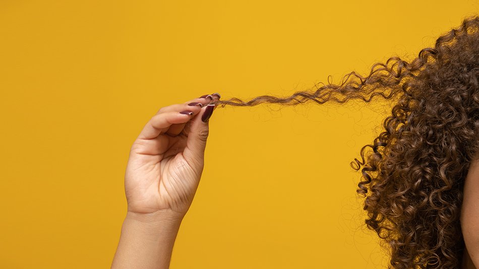 Kobieta trzyma pasmo mocno kręcących się włosów.