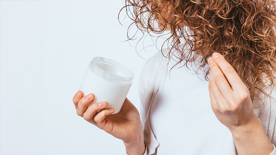 Kobieta trzyma w ręce maskę i nakłada ją na końce włosów