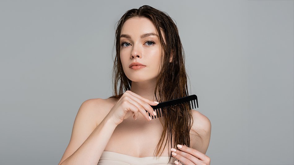 Młoda kobieta rozczesuje swoje włosy po zastosowaniu odżywki.