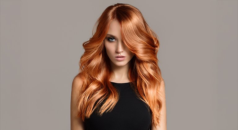 Kobieta z długimi falowanymi włosami zafarbowanymi na jasny rudy