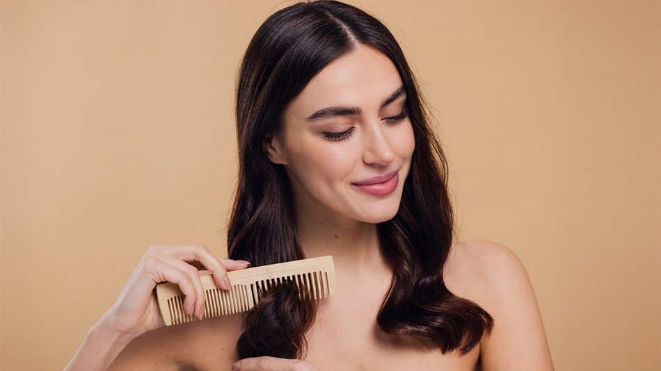 Kobieta czesząca gładkie falowane włosy po olejowaniu