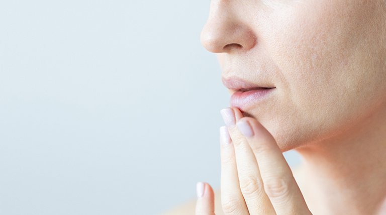 zdjęcie kobiety dotykającej podbródka na jasnoniebieskim tle