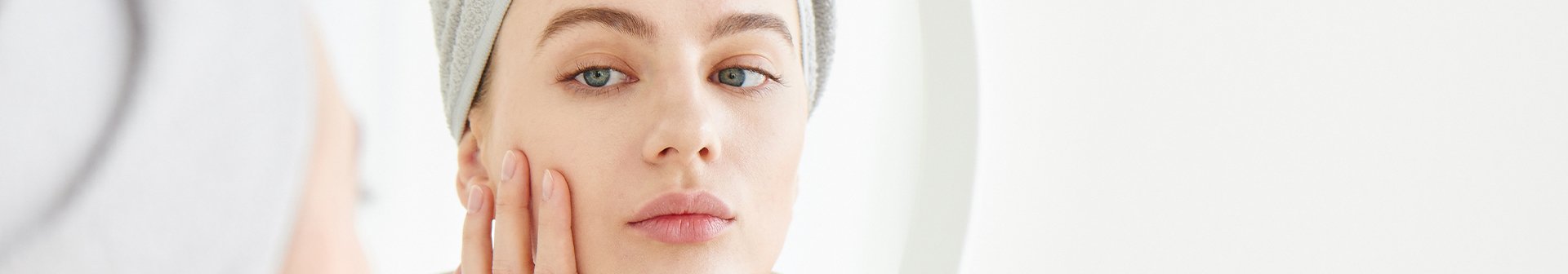 Kobieta oglądająca swoją cerę w lustrze - zdjęcie