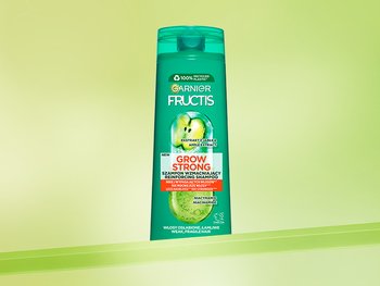 Ciemnozielona butelka szamponu Garnier Fructis, na limonkowym gradiencie