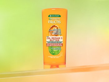 Pomarańczowa butelka Garnier Fructis, na zielono-żółtym gradiencie