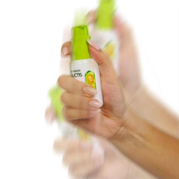 Mała butelka Garnier Fructis z grafiką cytryny energicznie wstrząsana dłonią, rozmycie ruchu Mała butelka Garnier Fructis z grafiką cytryny energicznie wstrząsana dłonią, rozmycie ruchu