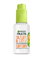 Termoochronne serum Garnier Fructis Sleek & Stay w białej butelce z zieloną pompką, na zielonym tle