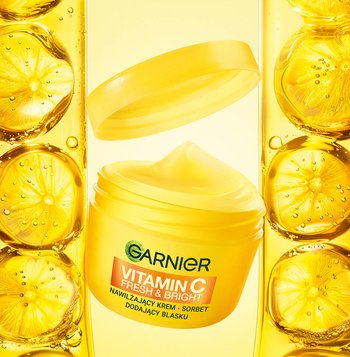 Żółty słoik kremu Garnier z witaminą C z unoszącą się pokrywką, na żółtym tle