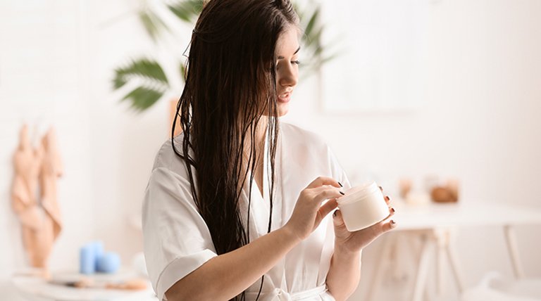 Kobieta z odkręconym słoiczkiem maski do włosów