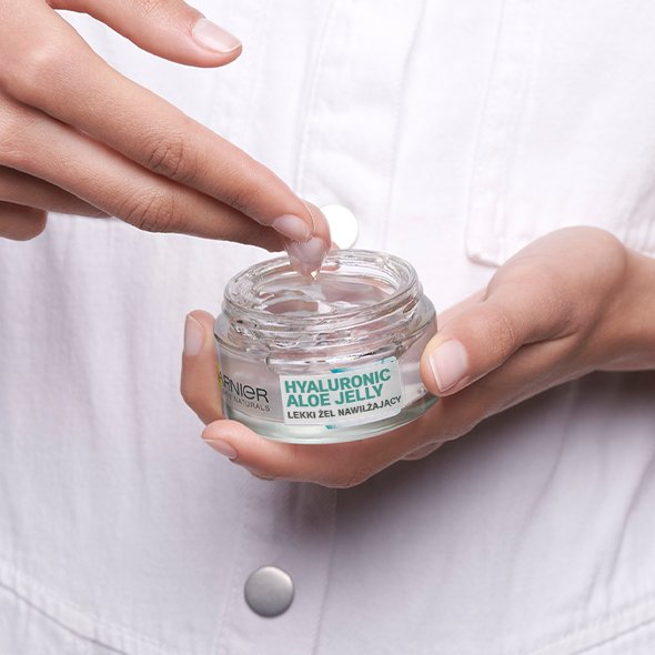 Dłonie trzymają szklany słoik żelu Garnier Hyaluronic Aloe Jelly, palce nabierają produkt Dłonie trzymają szklany słoik żelu Garnier Hyaluronic Aloe Jelly, palce nabierają produkt