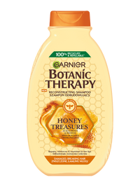 Żółta butelka szamponu Garnier Botanic Therapy z motywem miodu, na białym tle