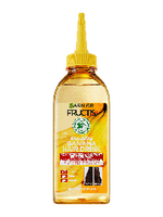 Przezroczysta, żółtawa butelka Garnier Fructis ze złocistym płynem i żółtym dziubkiem, na białym tle
