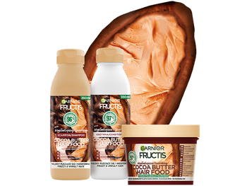 Trzy produkty Garnier Fructis Cocoa Butter Hair Food przed przekrojonym strąkiem kakaowca