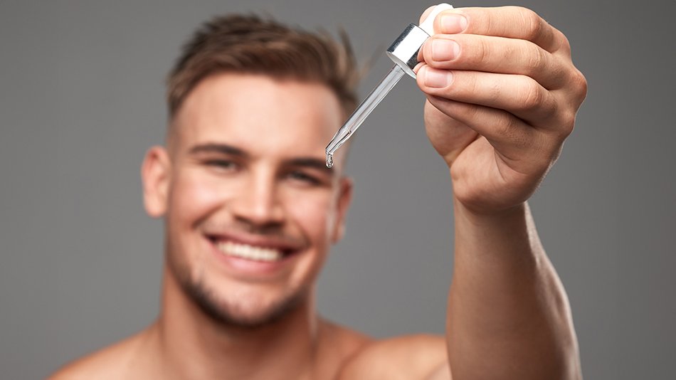 mężczyzna aplikujący serum do twarzy